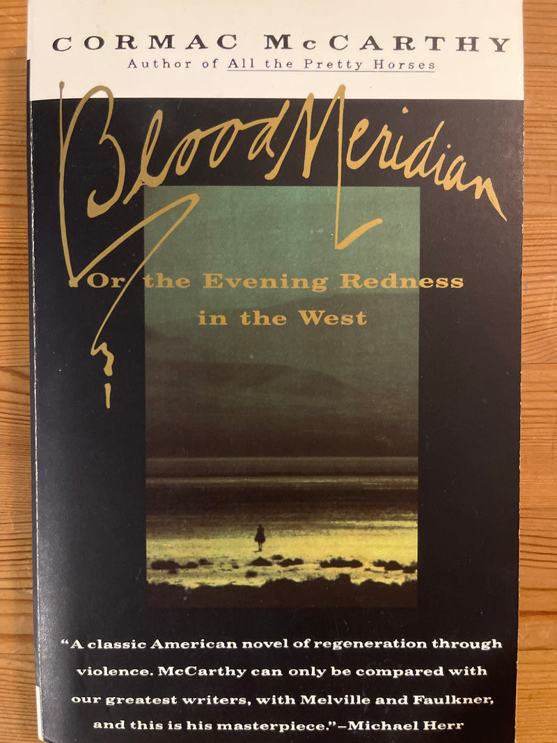 Pocket-utgave av Blood Meridian: Or the Evening Redness in the West av Cormac McCarthy, innbundet bok med svart omslag.