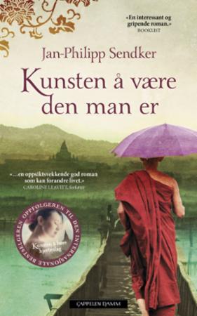 Innbundet roman "Kunsten å være den man er" av Cappelen Damm AS, bokomslag med tittel og forfatterinformasjon